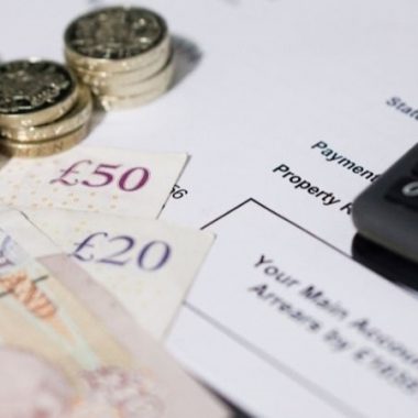 cash and a calculator sitting on top of an arrears notice letter to show key business figures