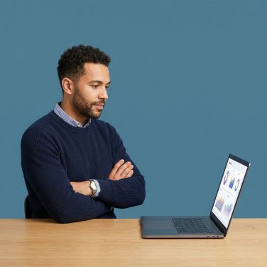A focused business professional analyzing performance charts on a laptop, evaluating the ROI and value of a business website.