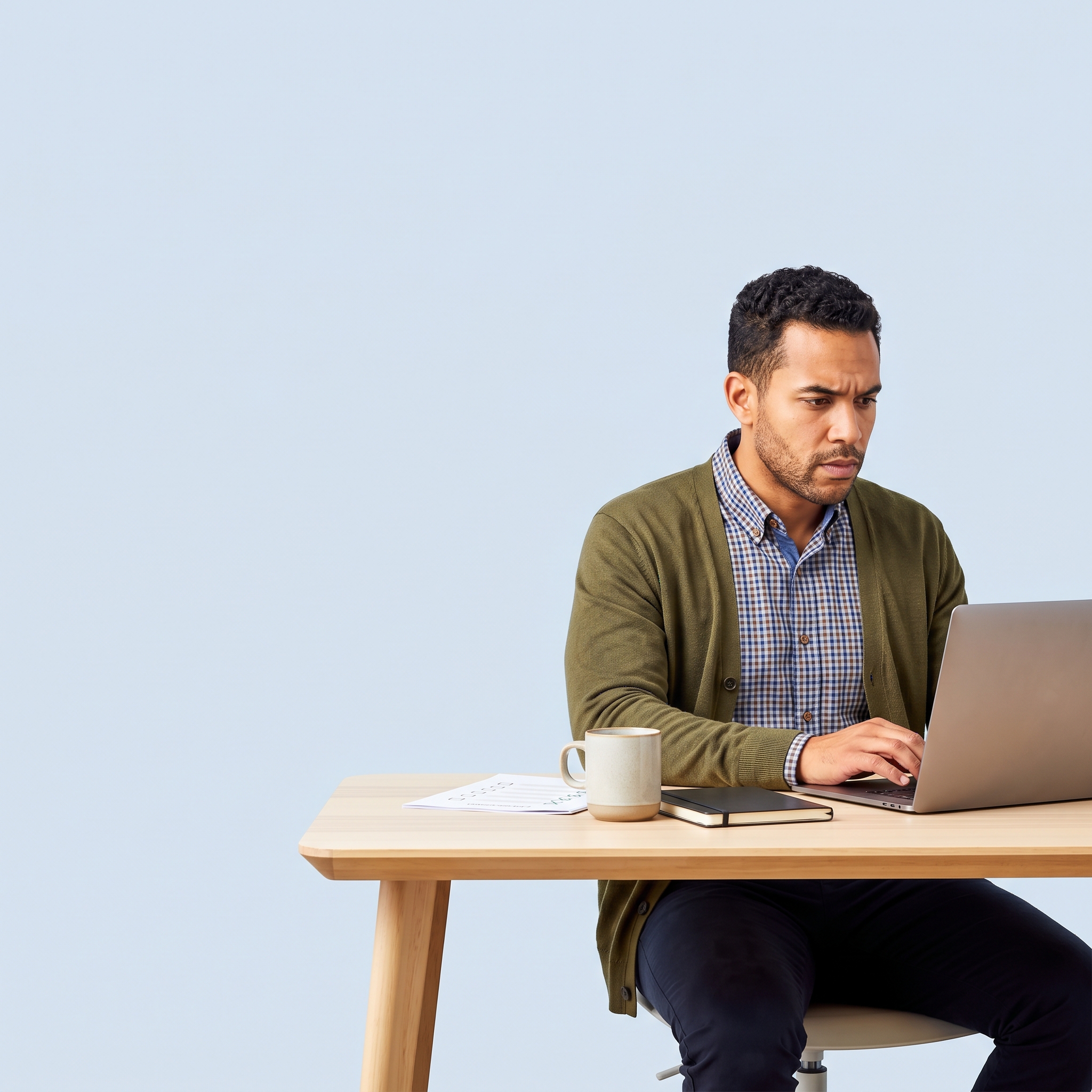 Small business owner reviewing a document at a desk, focused expression, plain light blue background