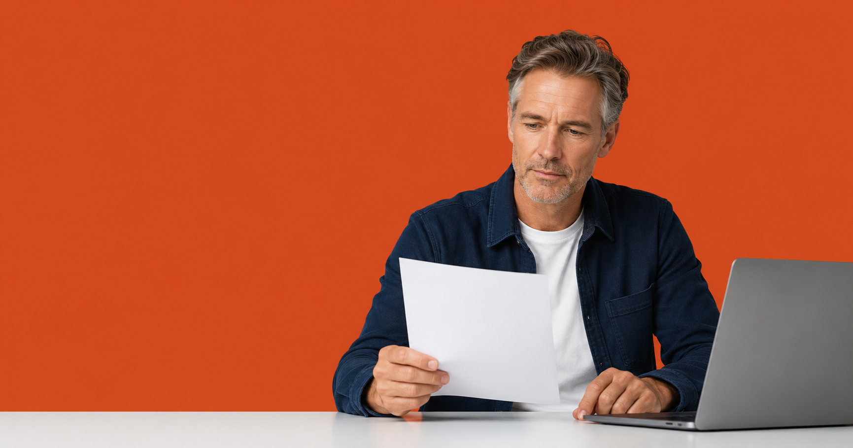 UK limited company director holding a single printed page above a clean desk with a laptop, calm focused expression.