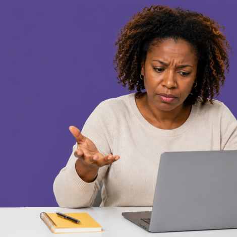 UK small business owner with a phone showing a Spam folder beside a laptop, working out why business emails are not landing in the inbox.