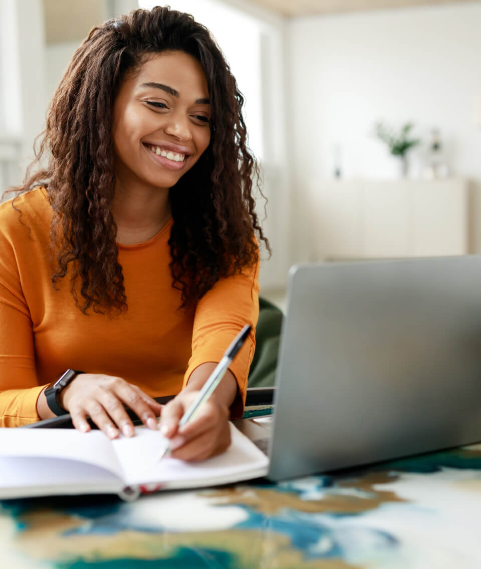 Woman smiling with a laptop and book